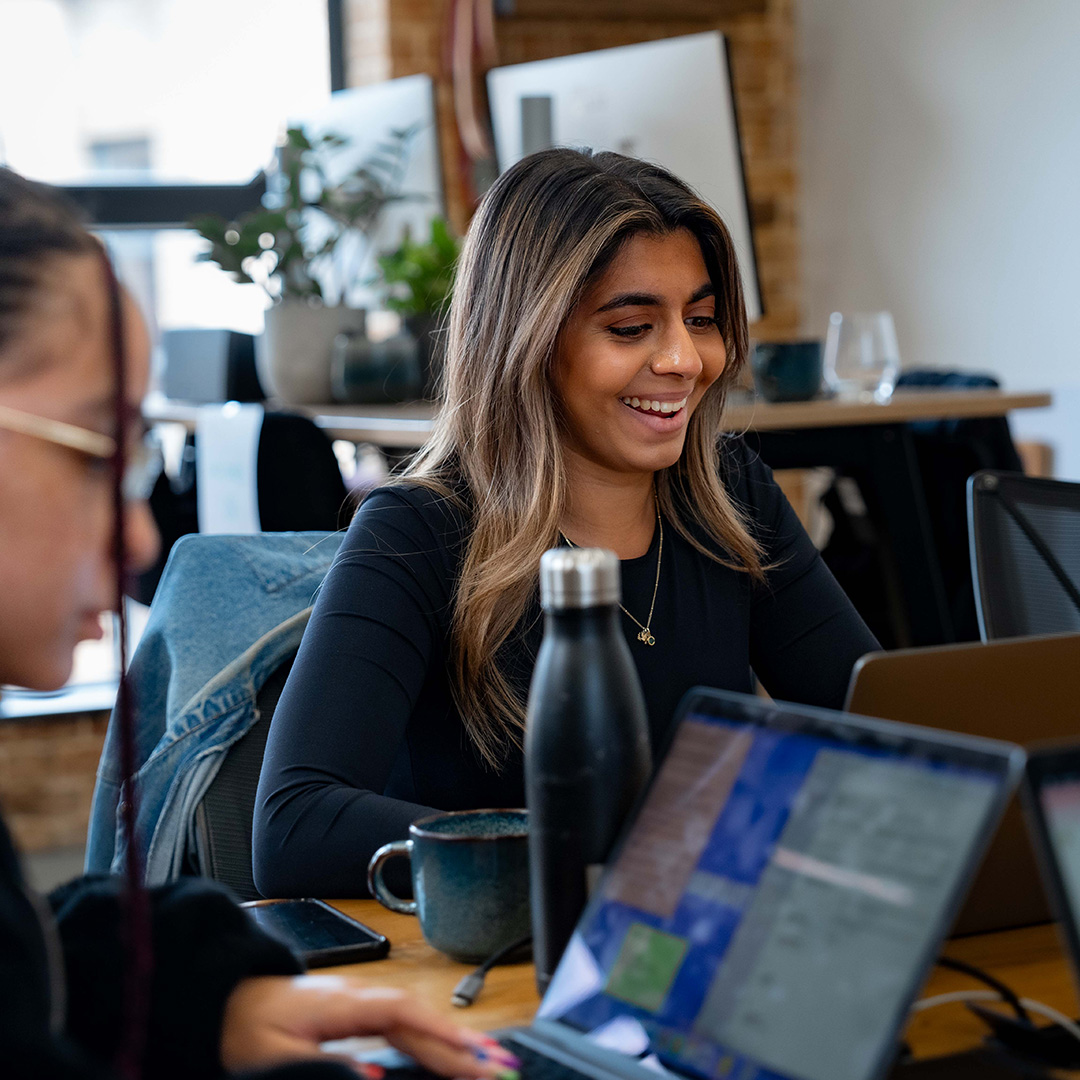 Image of young woman smiling while using laptop