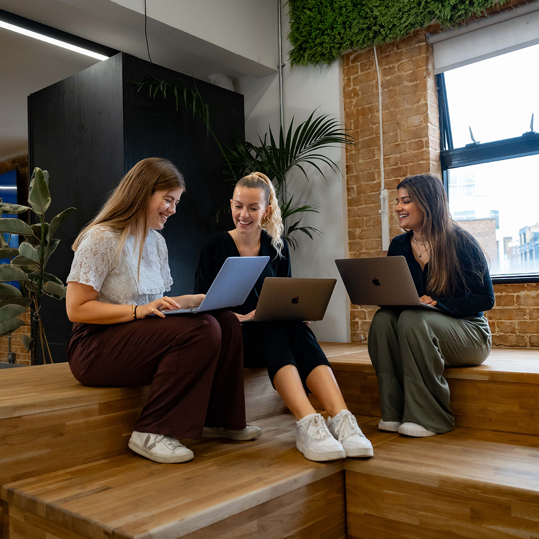 Image of three women smiling while working together