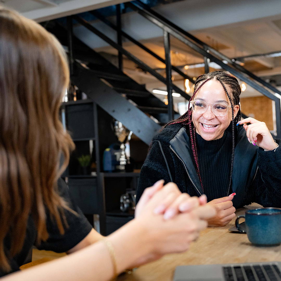 Image of young woman smiling at colleague with cups of tea