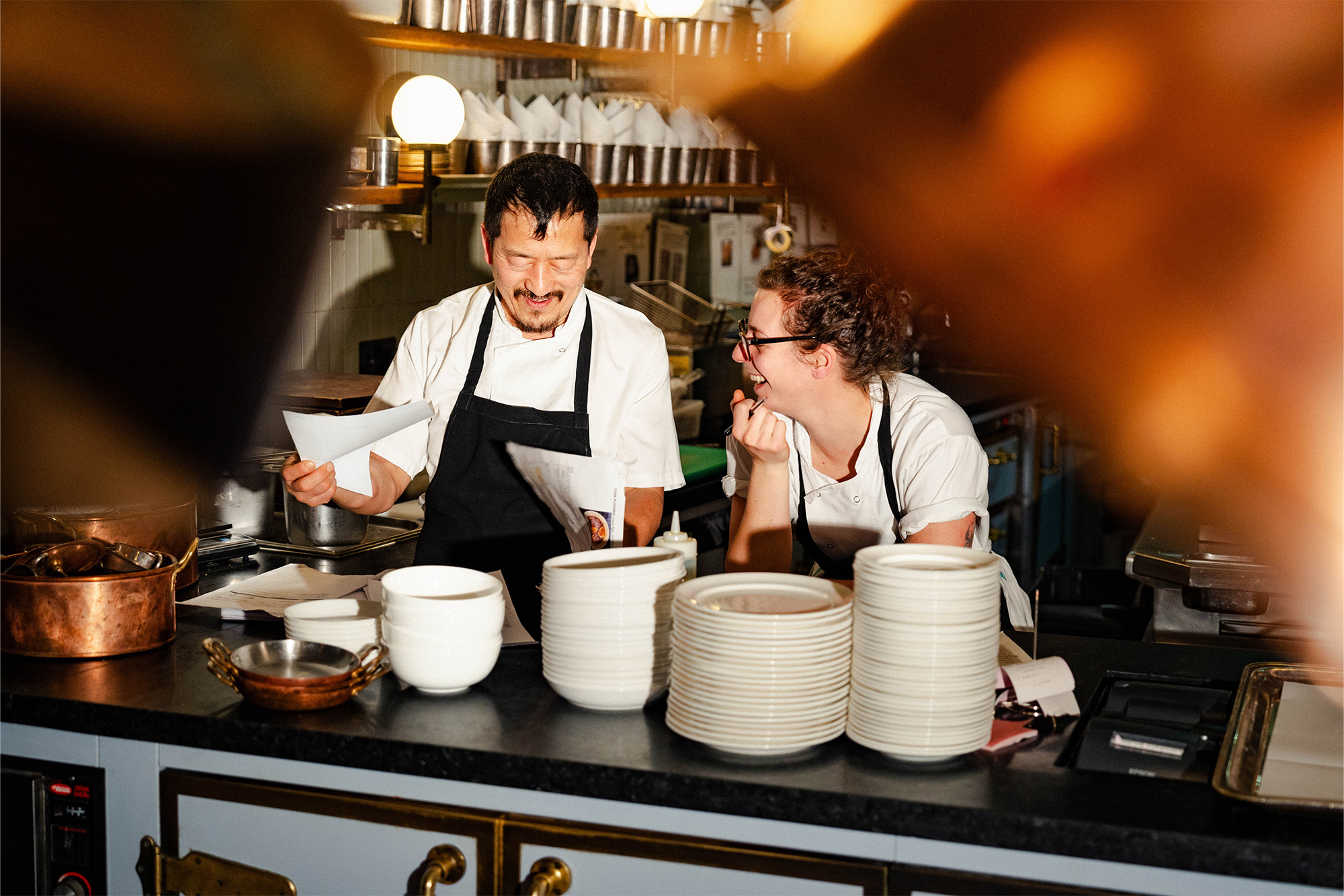 Two chefs in a Soho House kitchen laughing during menu selection