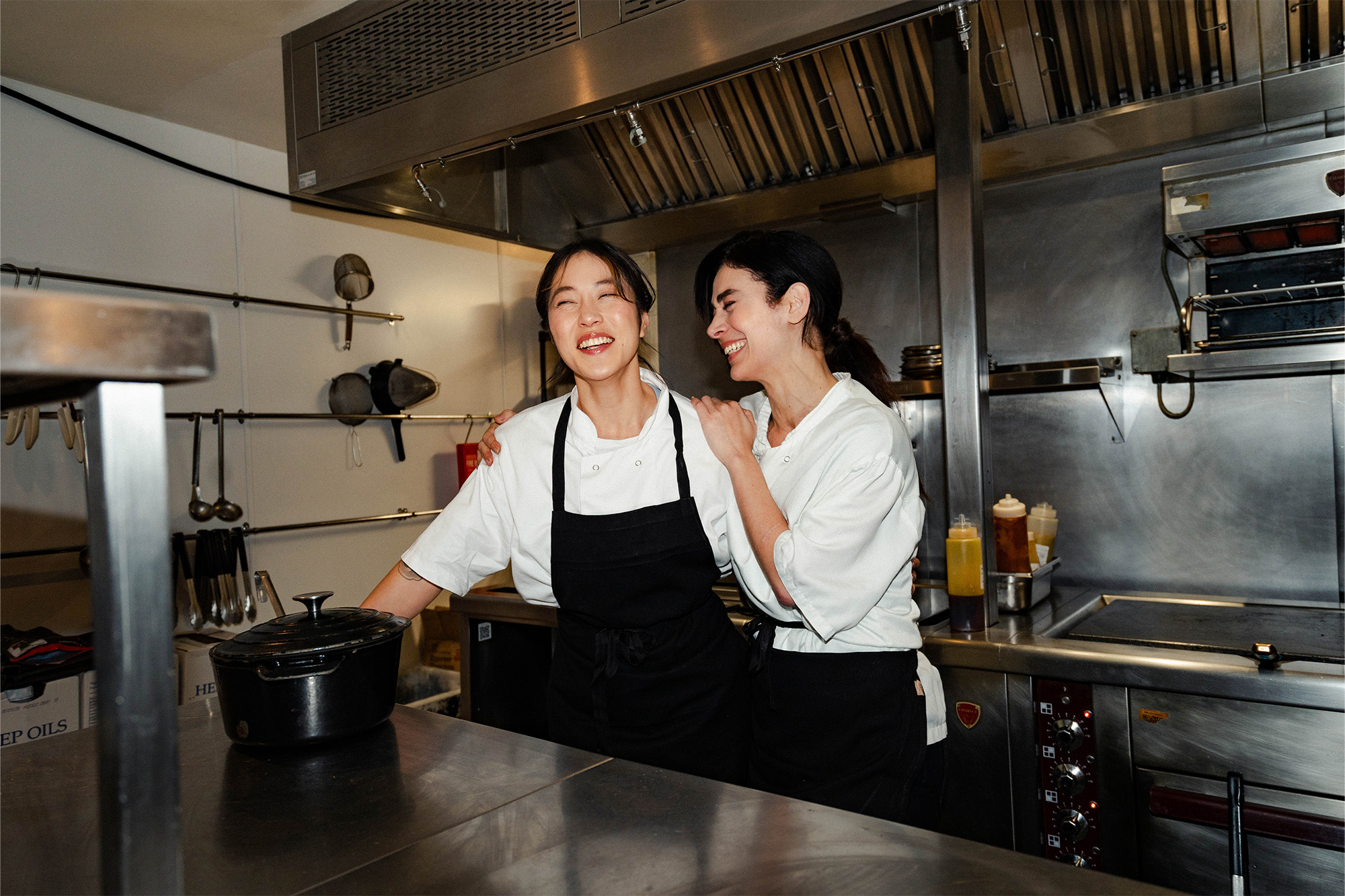 Two female chefs laughing together in the kitchen