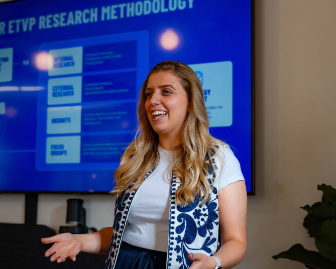 photo of female standing in front of a screen presenting