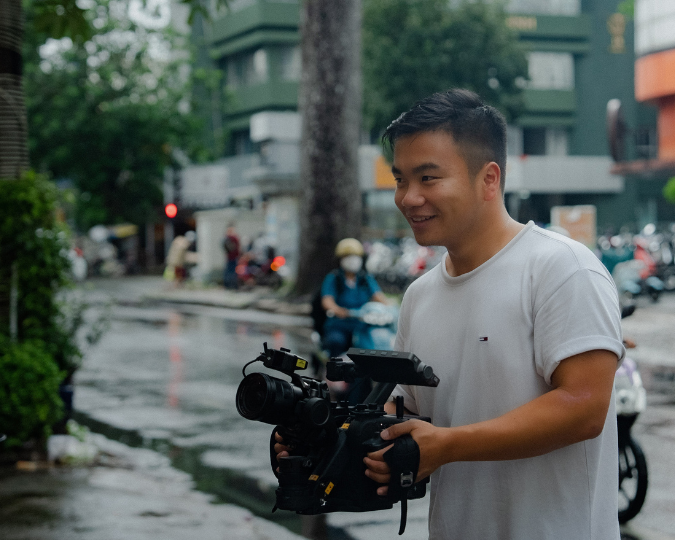 man holding film camera in the street smiling