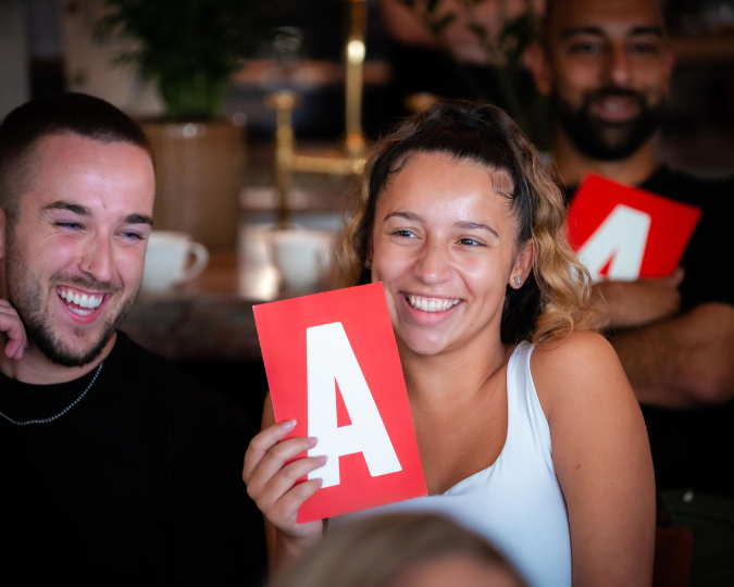 photo of male and female laughing the female is holding up at red a card