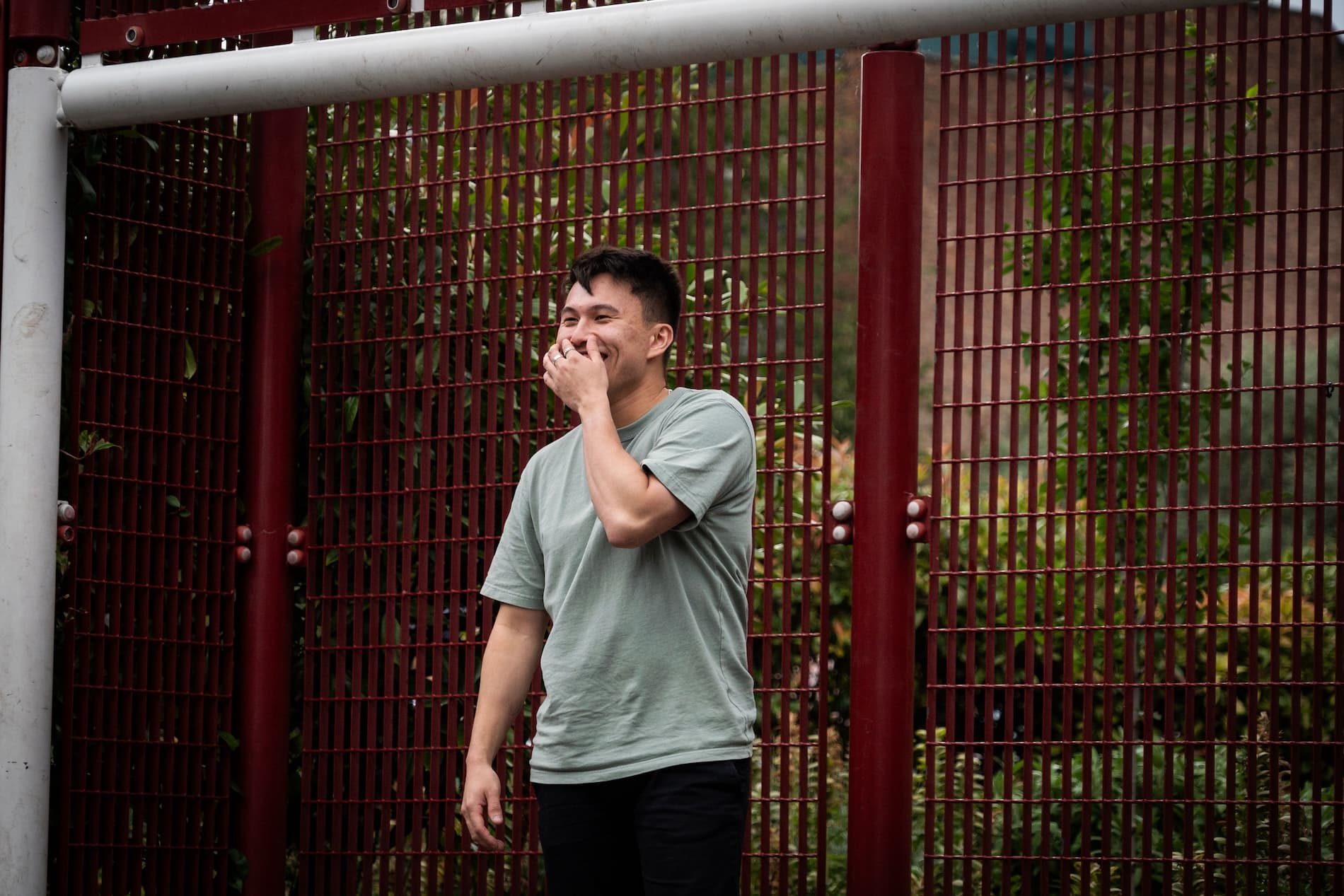 Man standing in between goal posts covering his laughter with his hand.