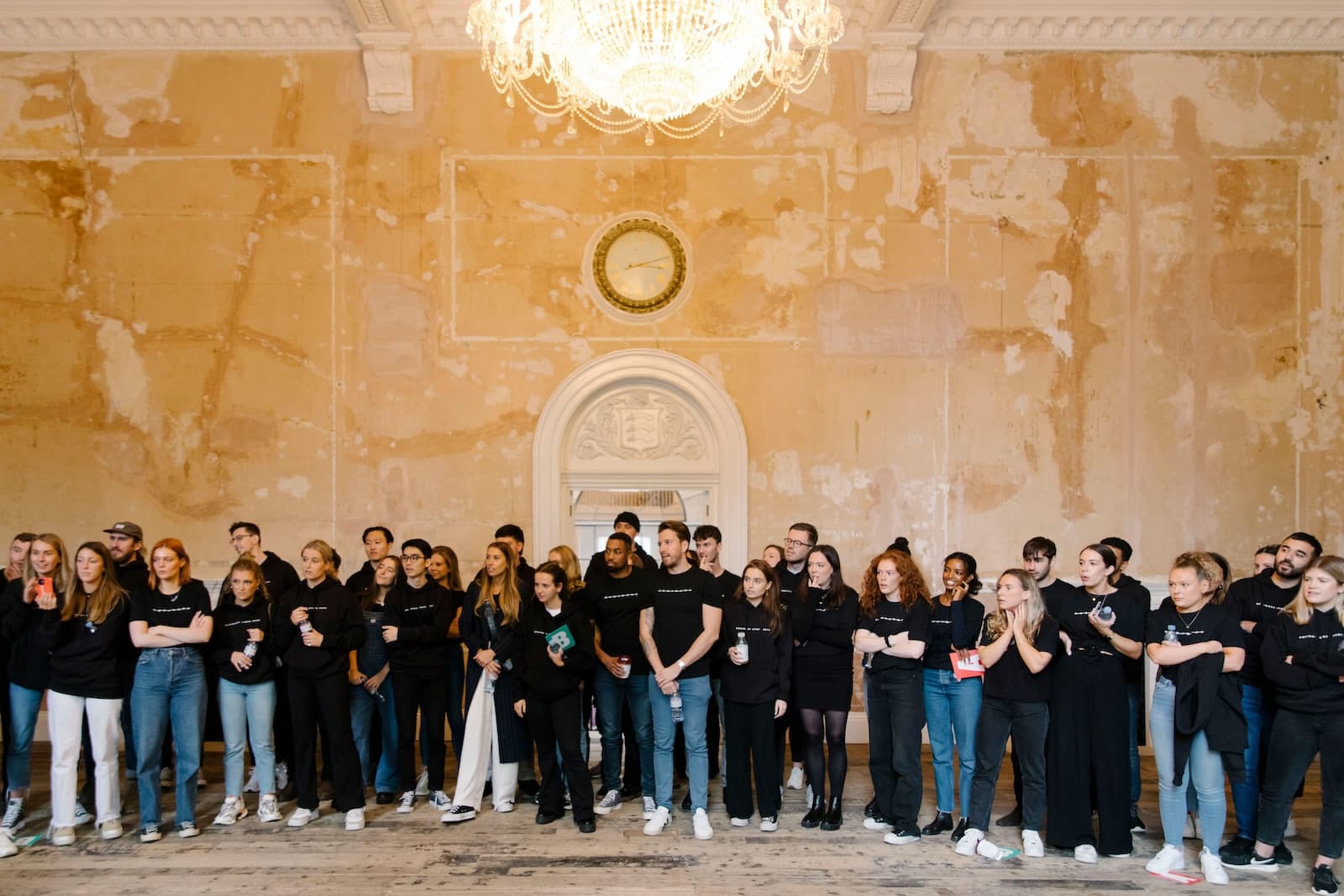 Wiser employees stand in a line against a plain wall with a clock.