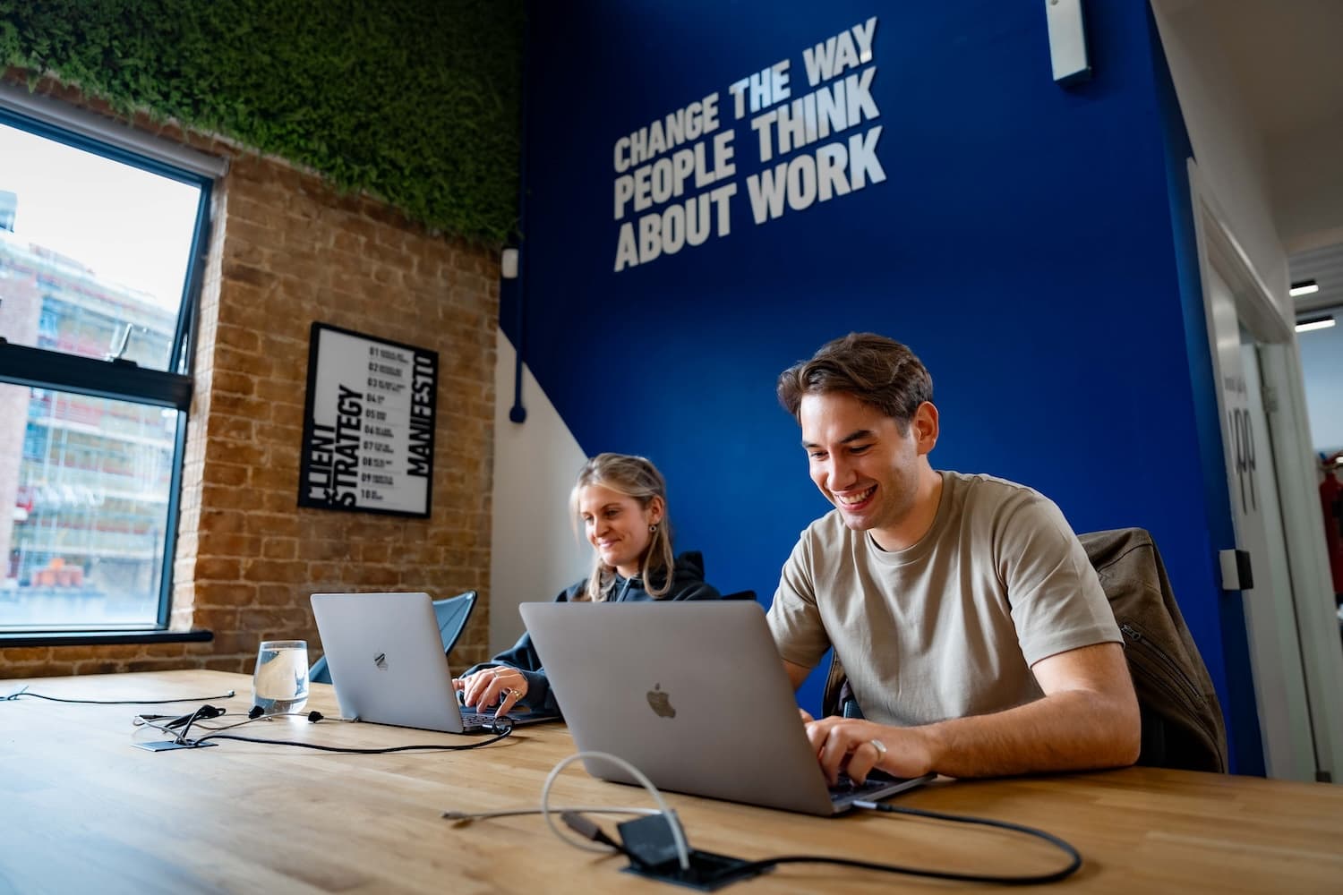 Man and woman sat at their desk on their lap tops.