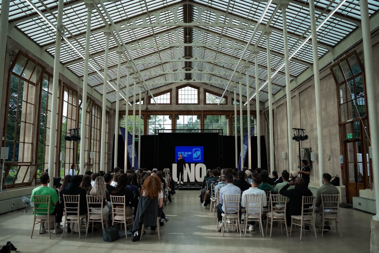 Wide shot of Wiser's CEO presenting to the company in a grand hall.