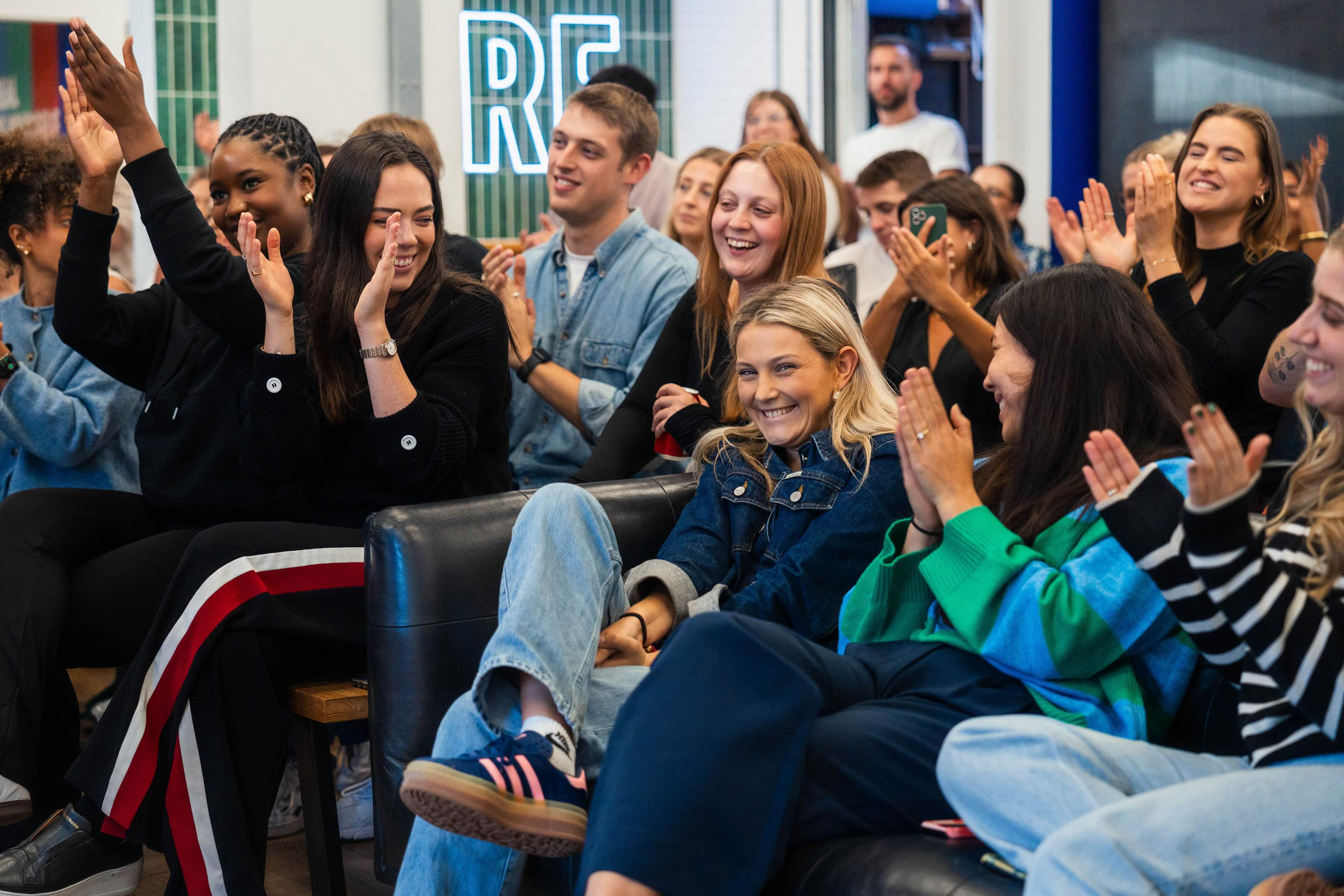 Photo of crowd clapping with blonde female smiling