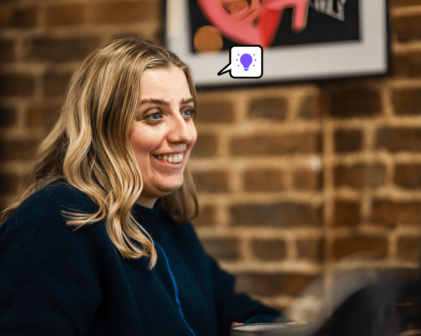 Photo of blonde female in a blue jumper looking at a laptop
