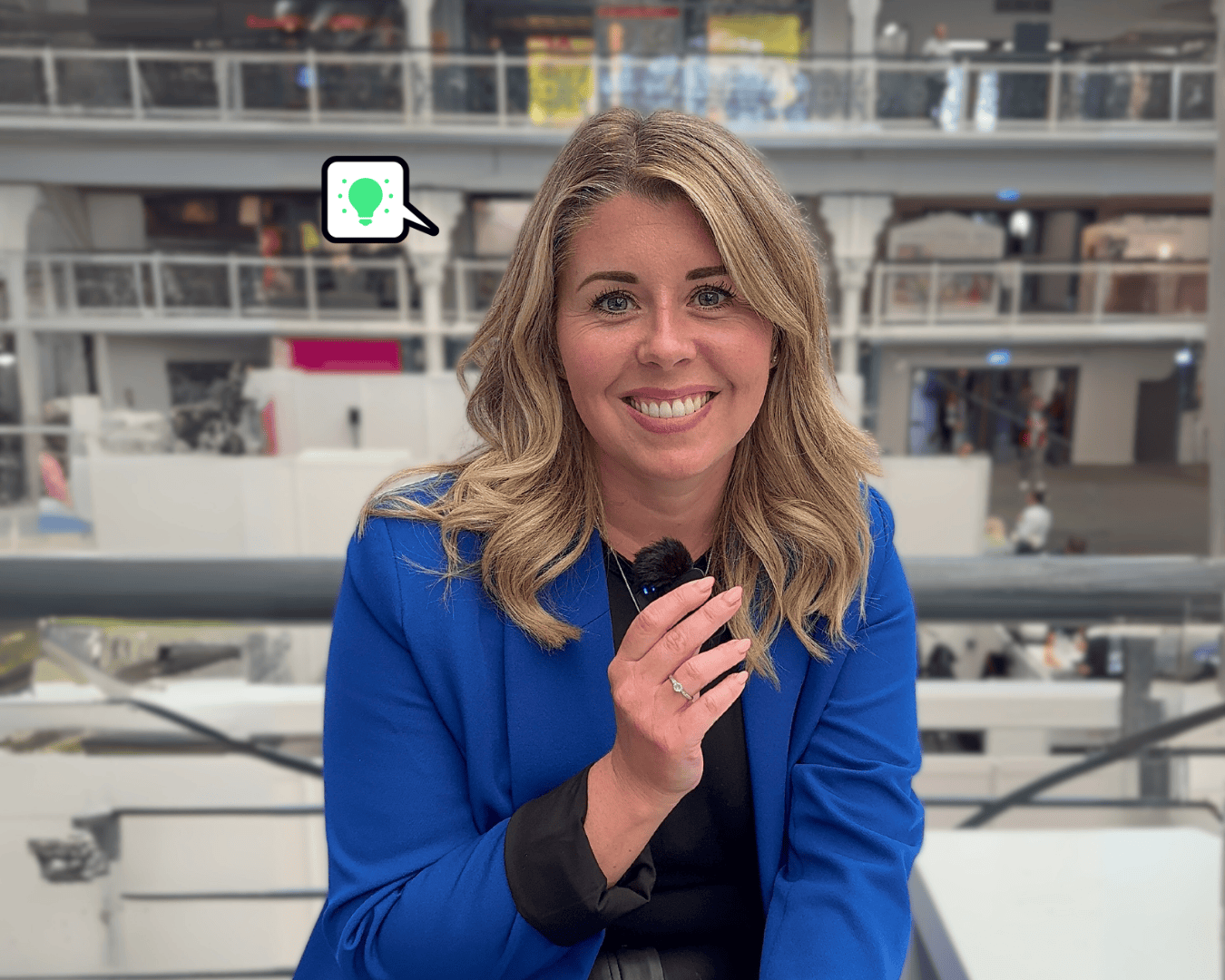 Photo of blonde female in blue jacket holding a mini microphone