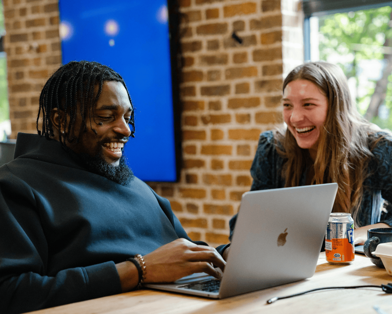 Photo of male and female laughing at a desk