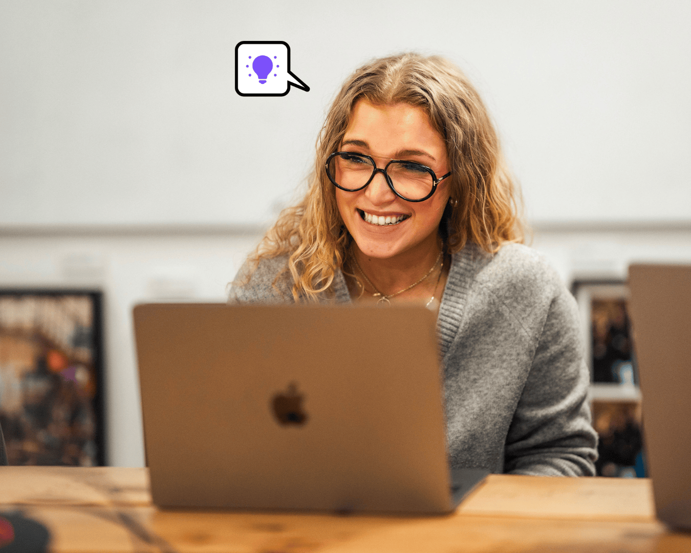 Photo of blonde female laughing in a grey jumper and glasses with a laptop