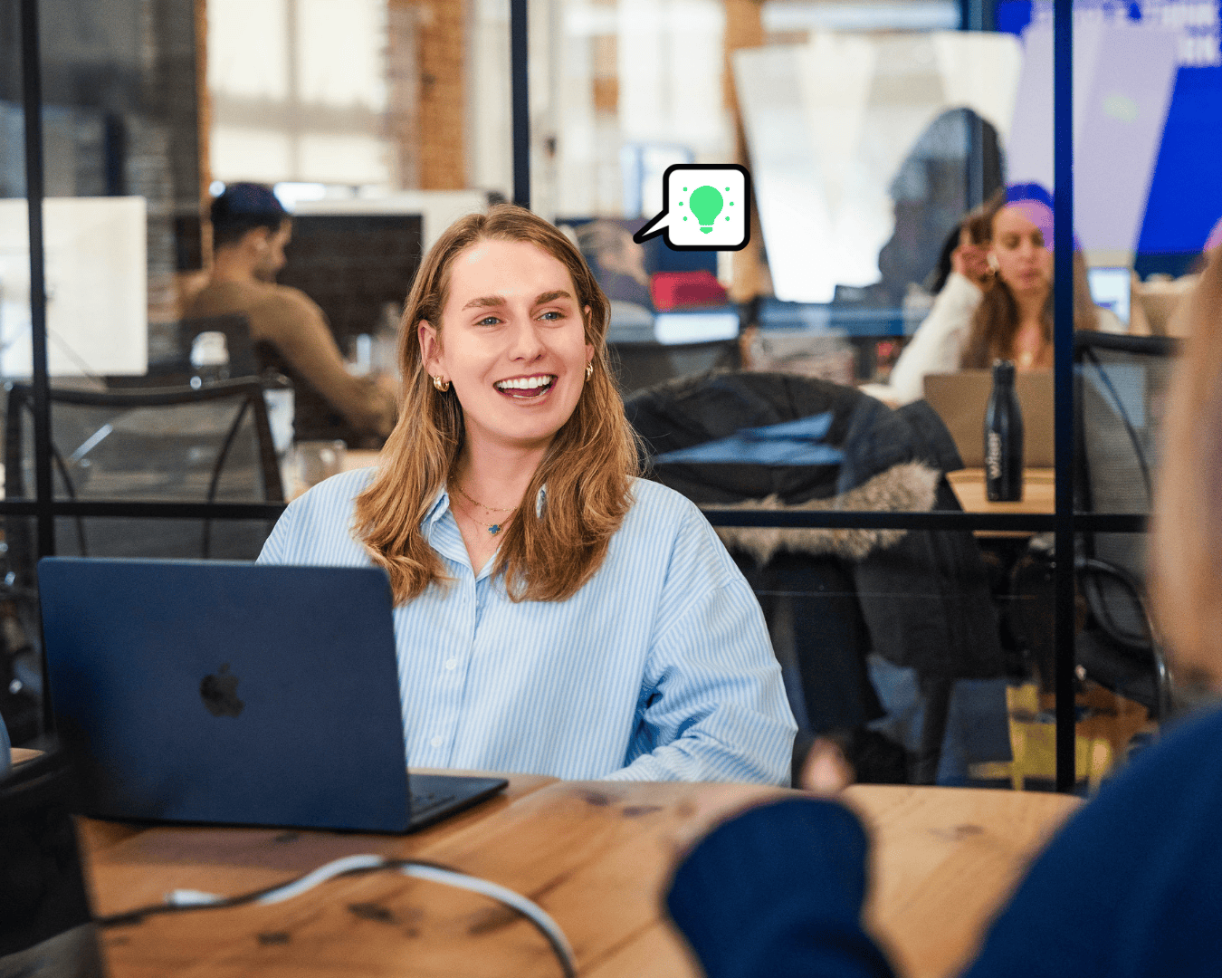 white female with brown hair and a blue shirt smiling in a meeting room w