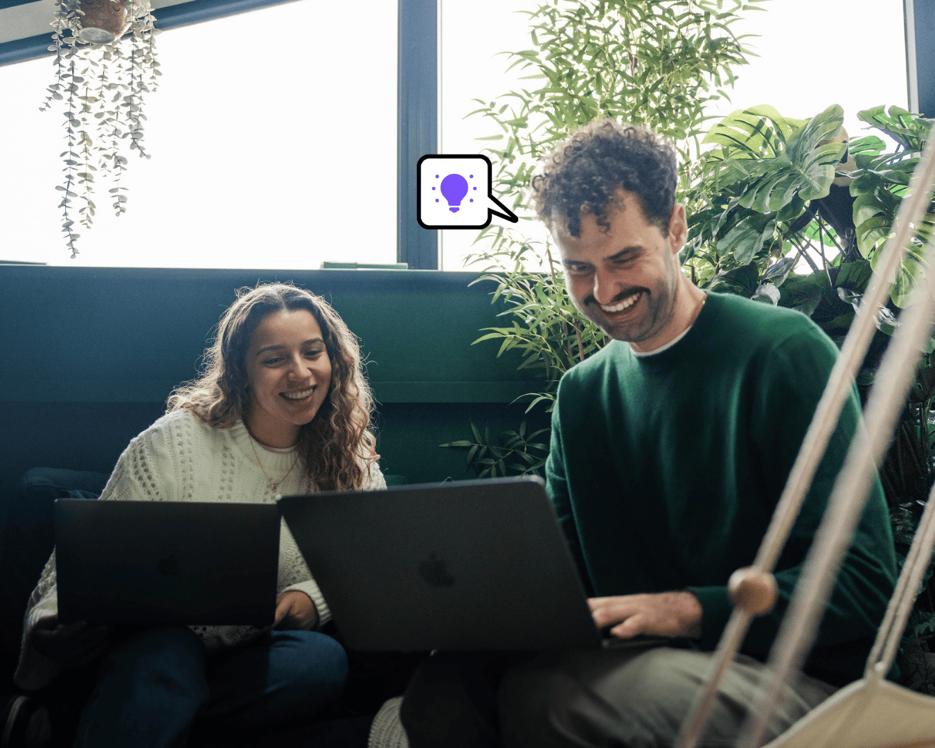 Photo of male and female looking a laptop screen in the office rainforest