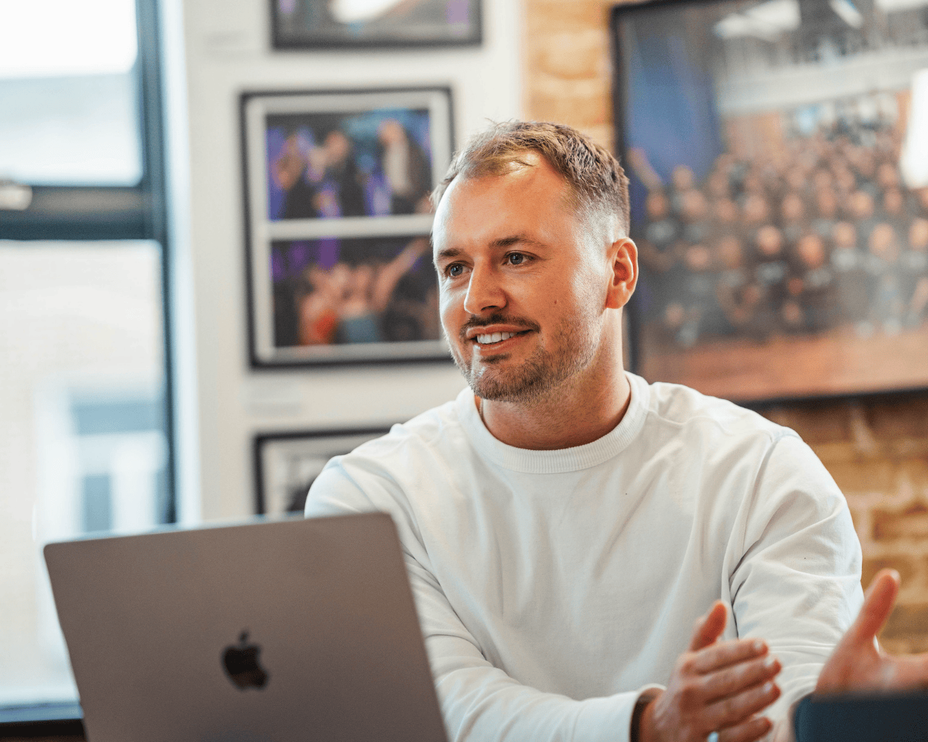 Photo of male in a white jumper smiling in a meeting