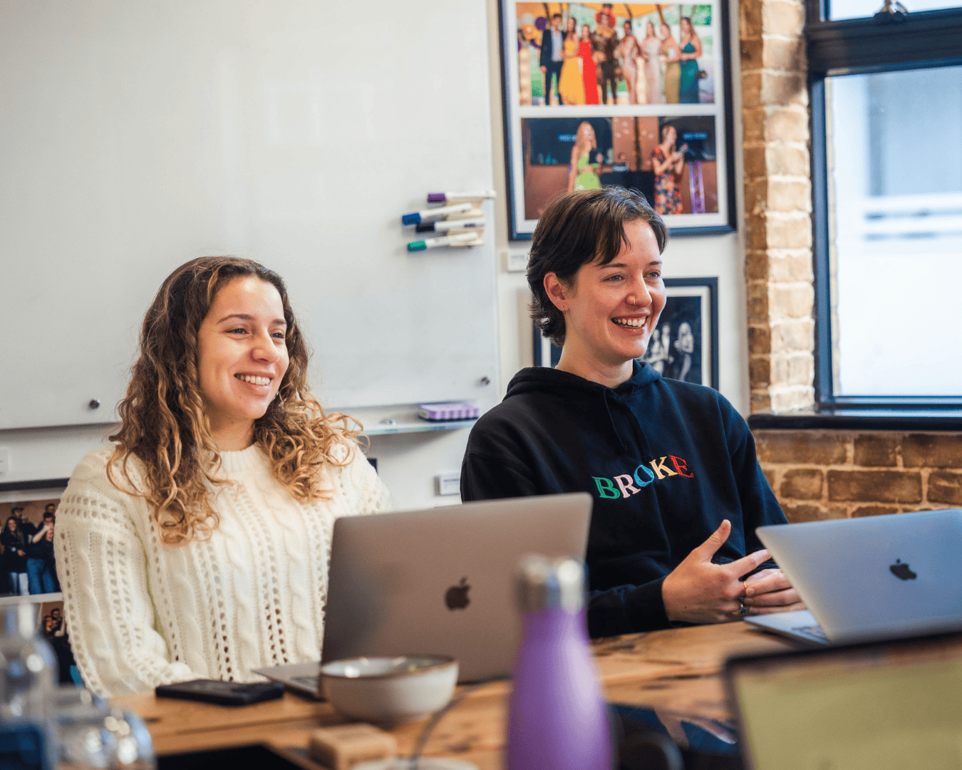 Photo of two females sat at desk laughing