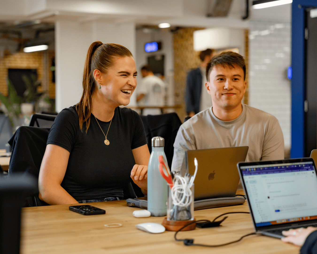 Photo of male and female at a desk in an office with laptops in front of them