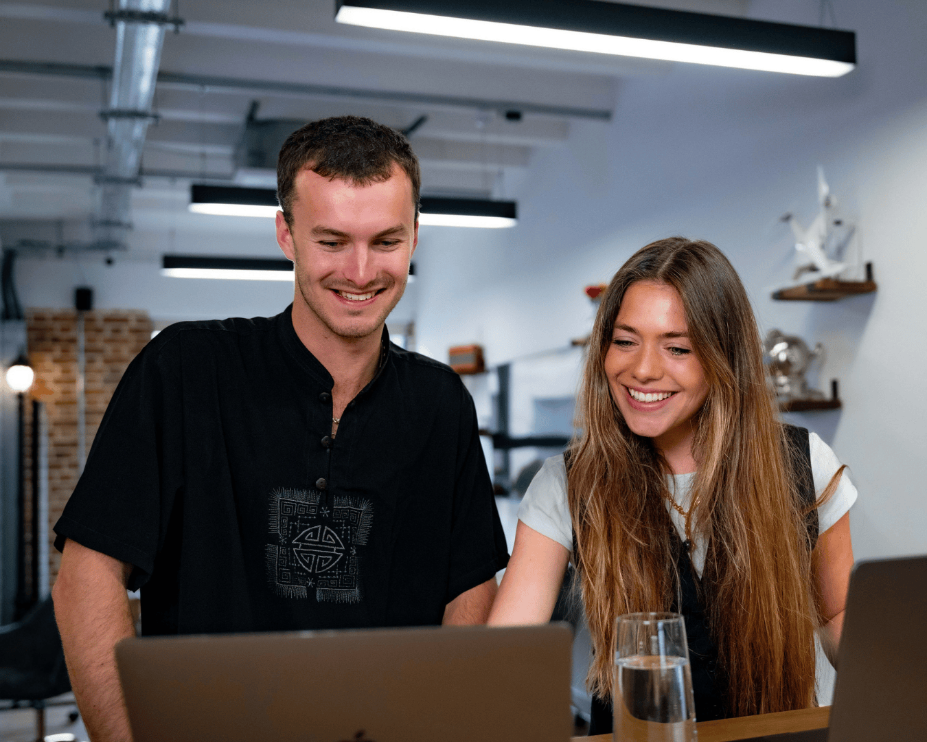 Photo of brunette male and female looking at a laptop screen smiling