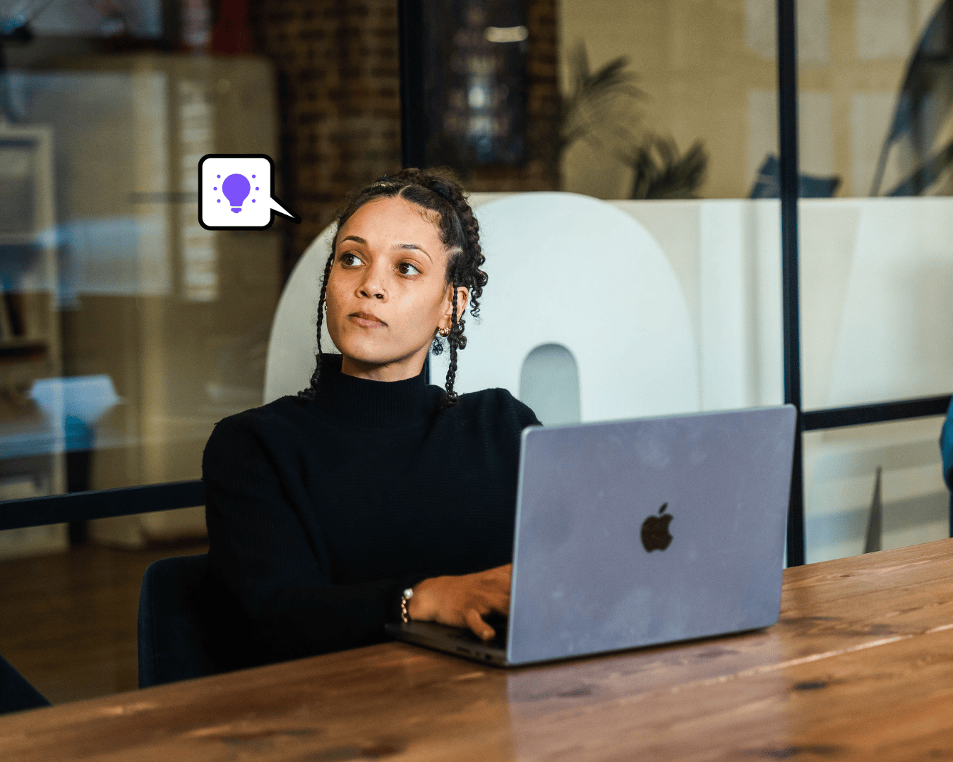 Photo of female sat at a desk looking at a screen with a laptop in front of her