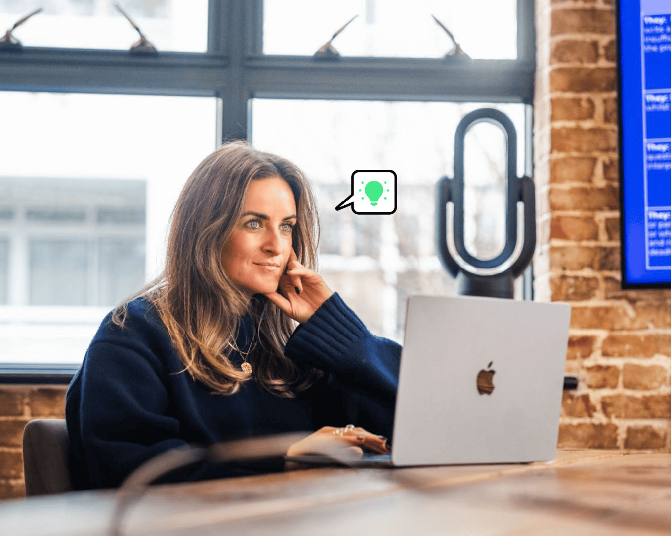 Brown hair women sat at a desk with a laptop in front of her laptop