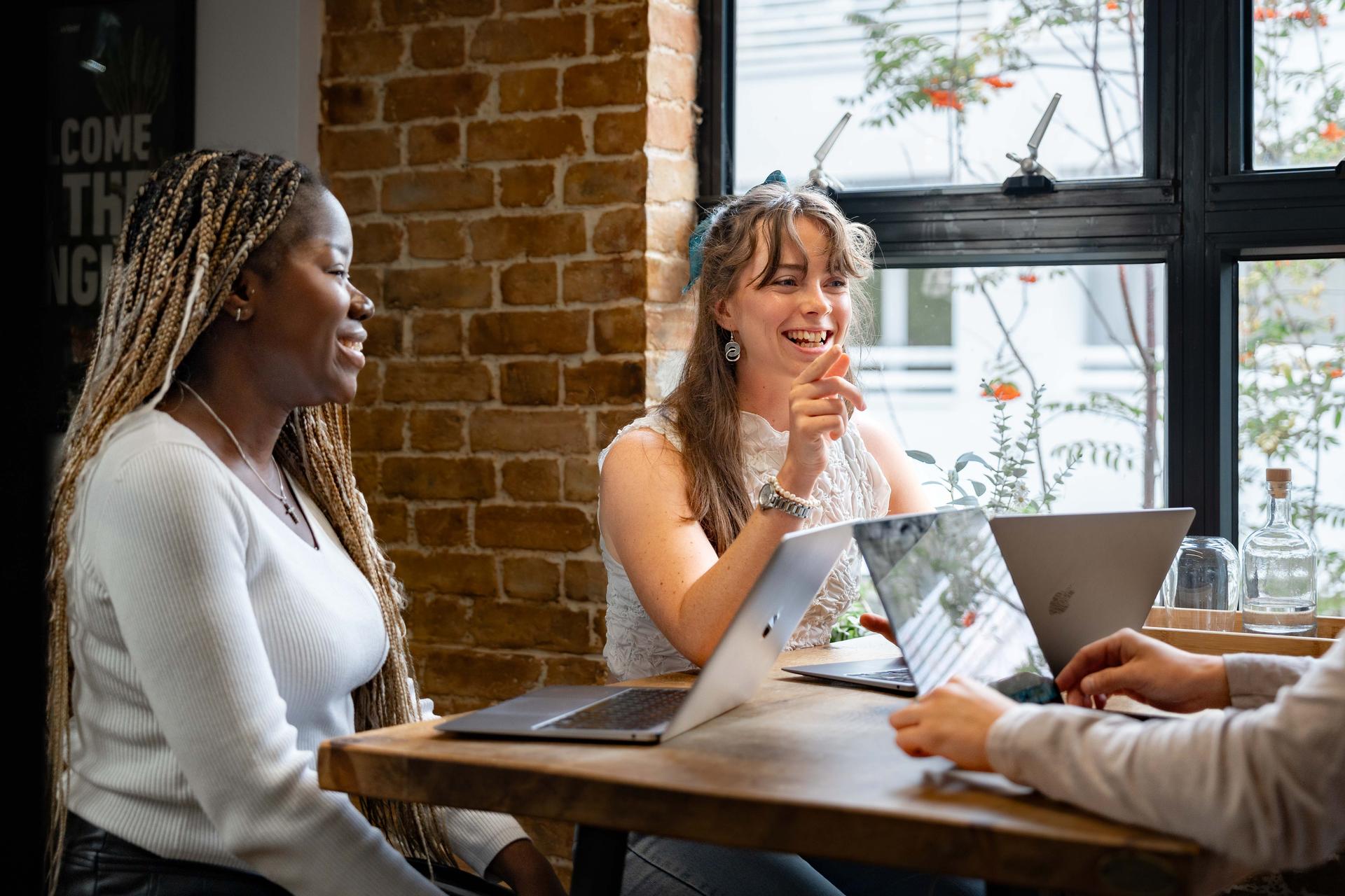 Two women sat at a desk laughing