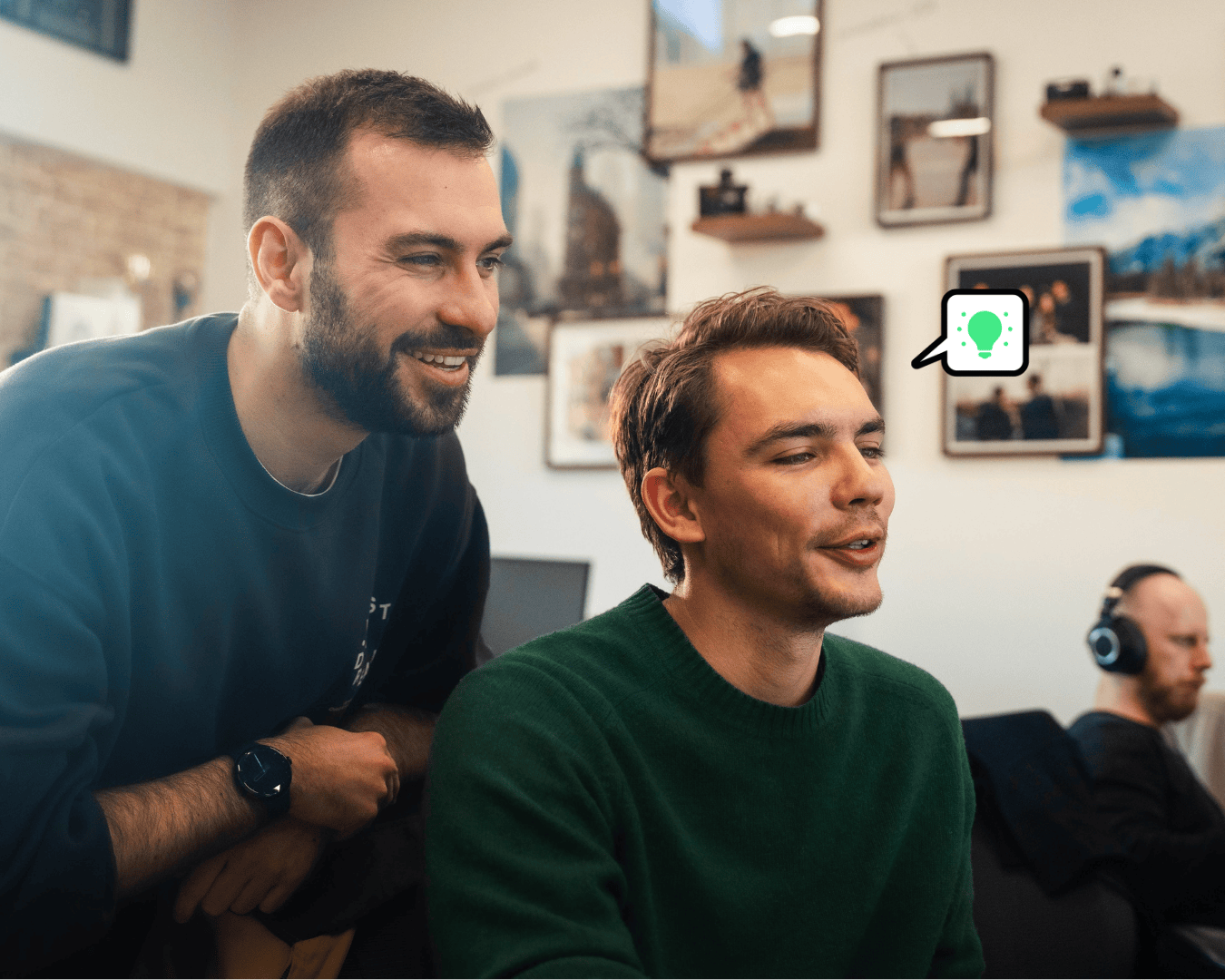 Two males with brown hair looking at a computer screen smiling