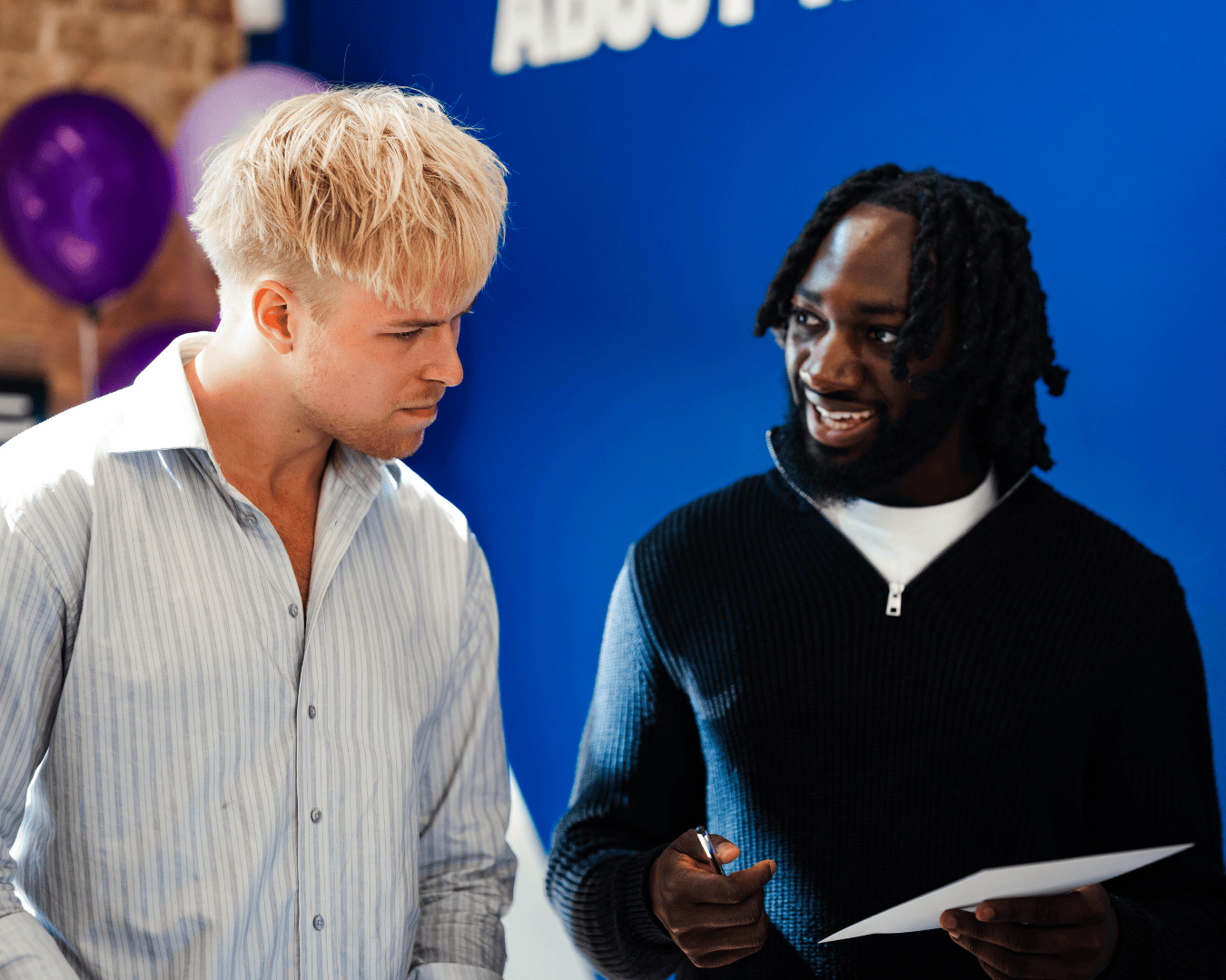 Two males looking a card smiling