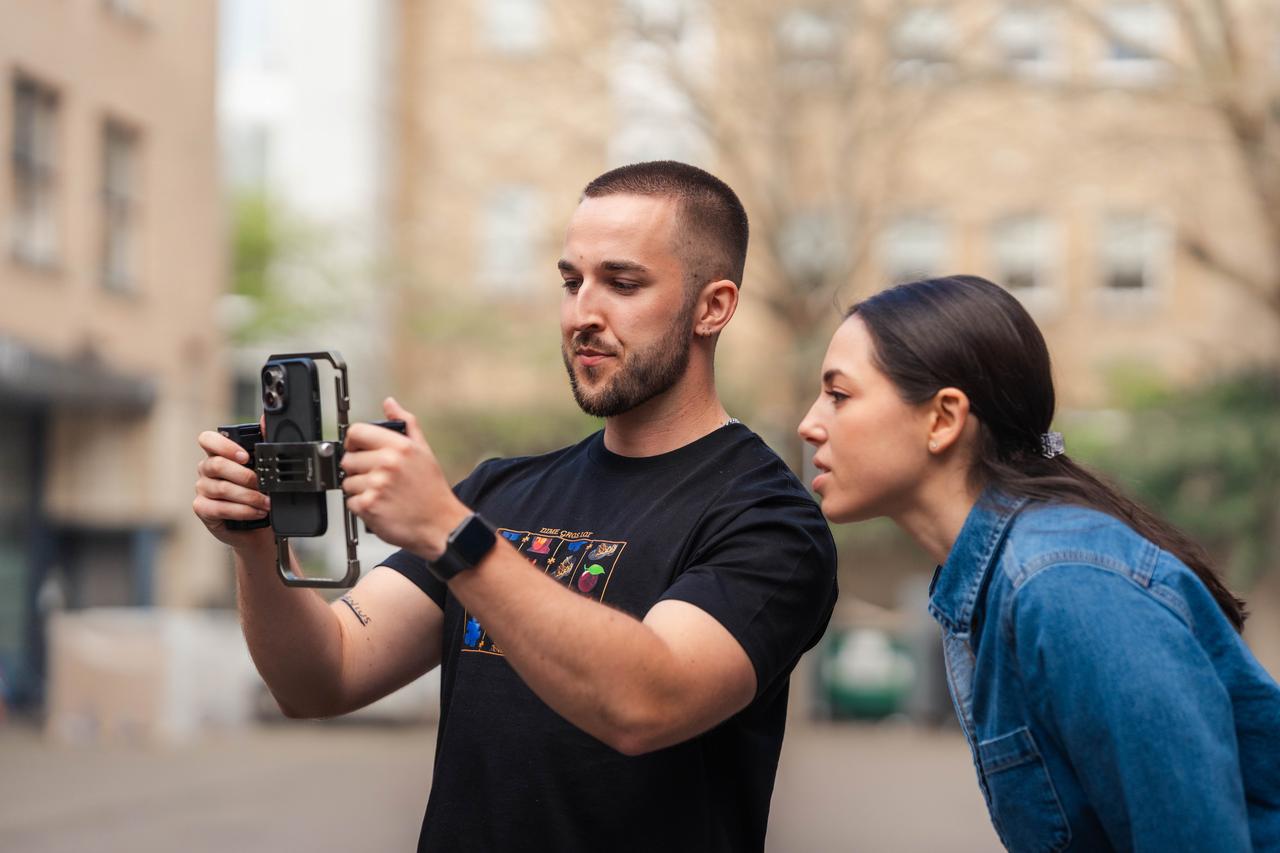 A white man with a buzz cut holds a phone rig while a woman with dark hair in a ponytail observes. They create content for DNV’s EVP activation strategy.