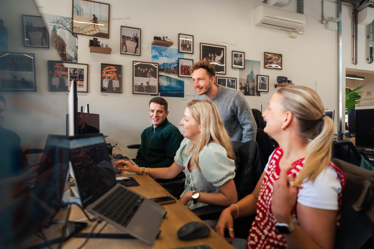 Two women and two men of varied ethnicities collaborate in a creative office. Captures social media advocacy training and global employer branding during DNV’s employee advocacy initiative.