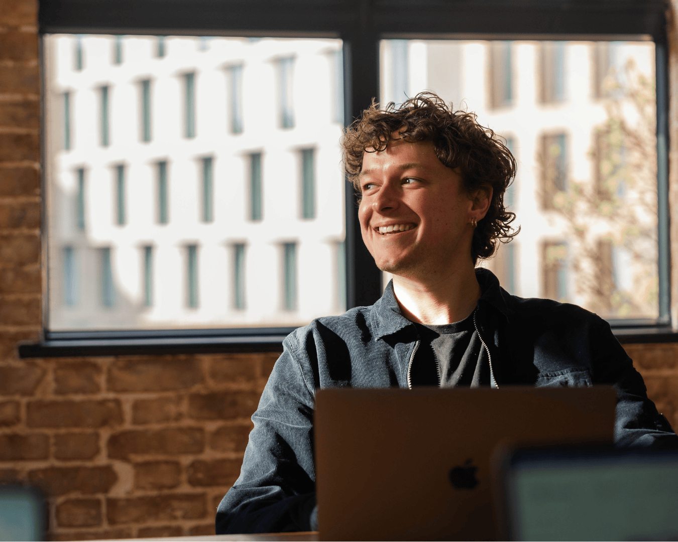 Photo of male with brown curly hair smiling wearing a black jacket