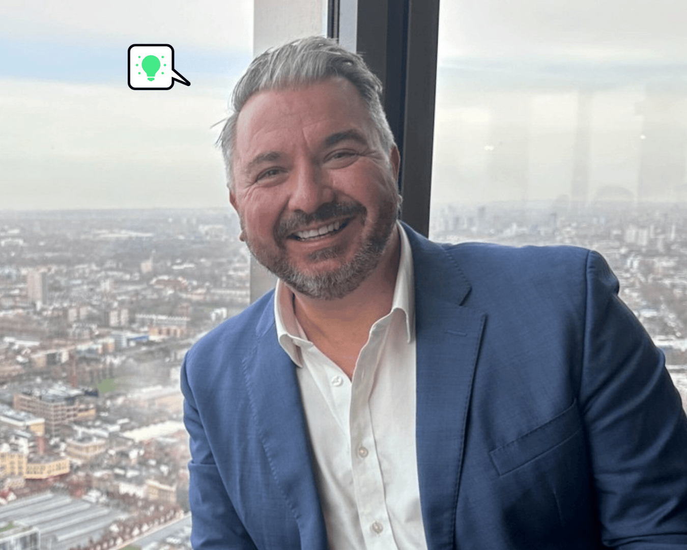 photo of a male in a blue blazer with a white shirt on. With a sky line view in the background