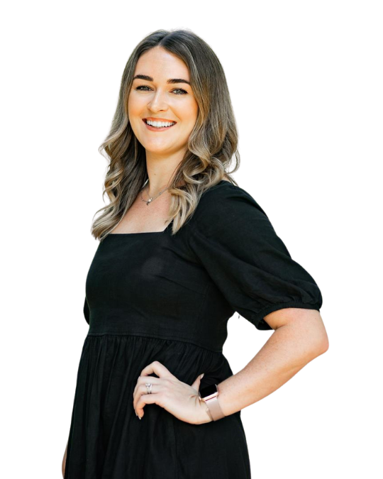 Happy smiley woman in her thirties looks confident with her hand on her hip. She's wearing a black short sleeve dress with blonde and brown coloured waved hair