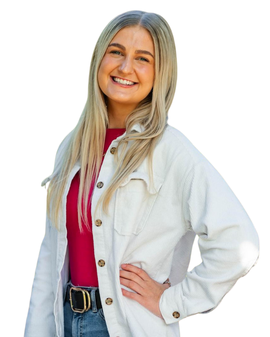Blonde white woman smiles wearing a white denim jacket, a pink t-shirt and blue jeans