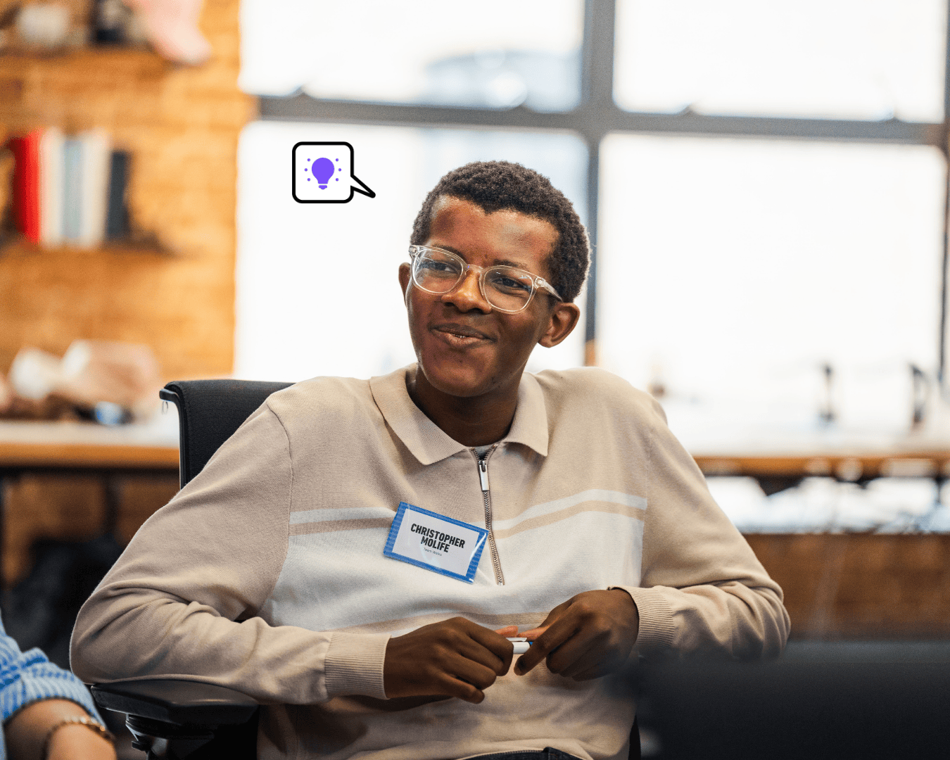 Photo of man with glasses and black hair smiling. Wearing a beige jumper