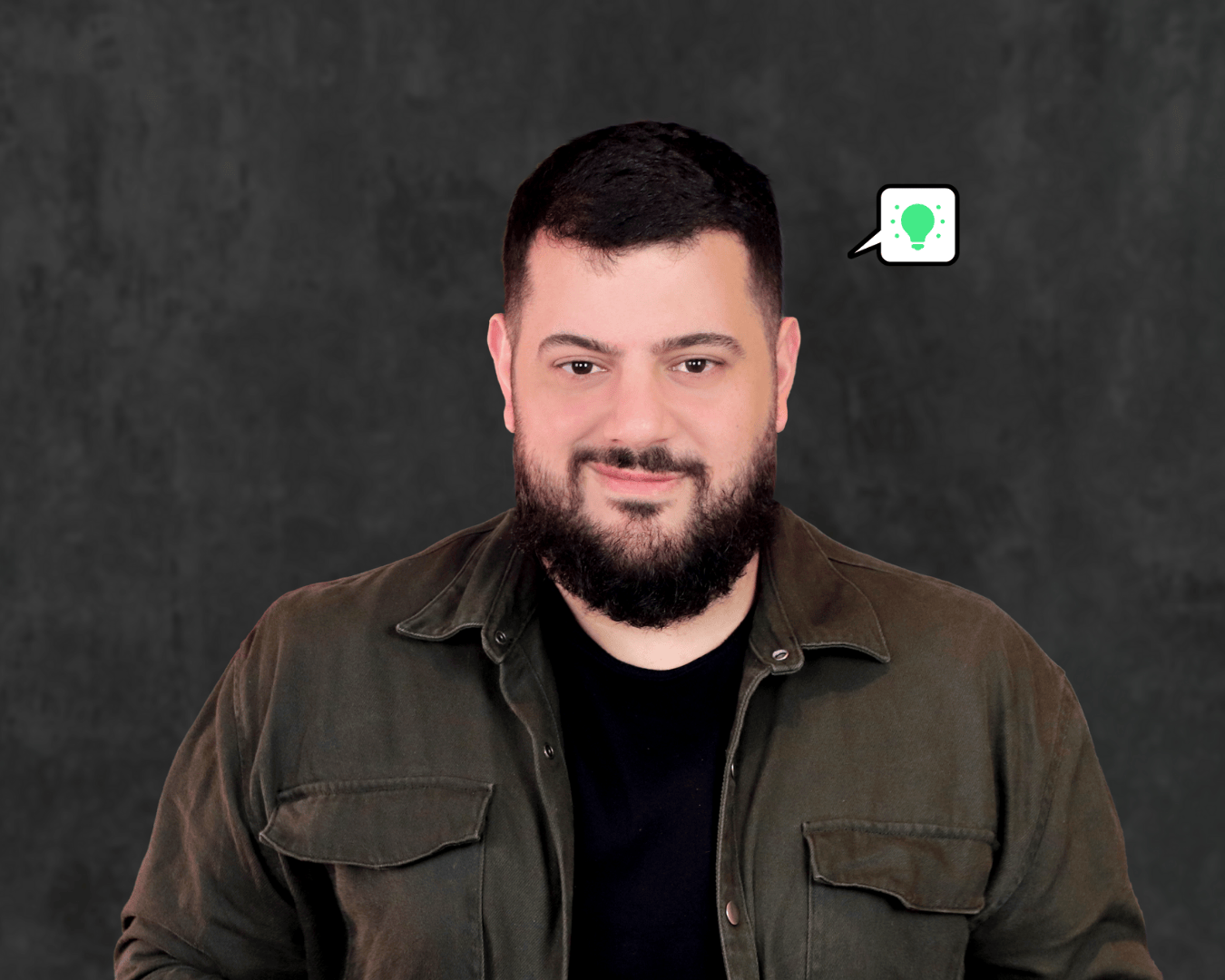 photo of a man with black hair and beard, with a grey background