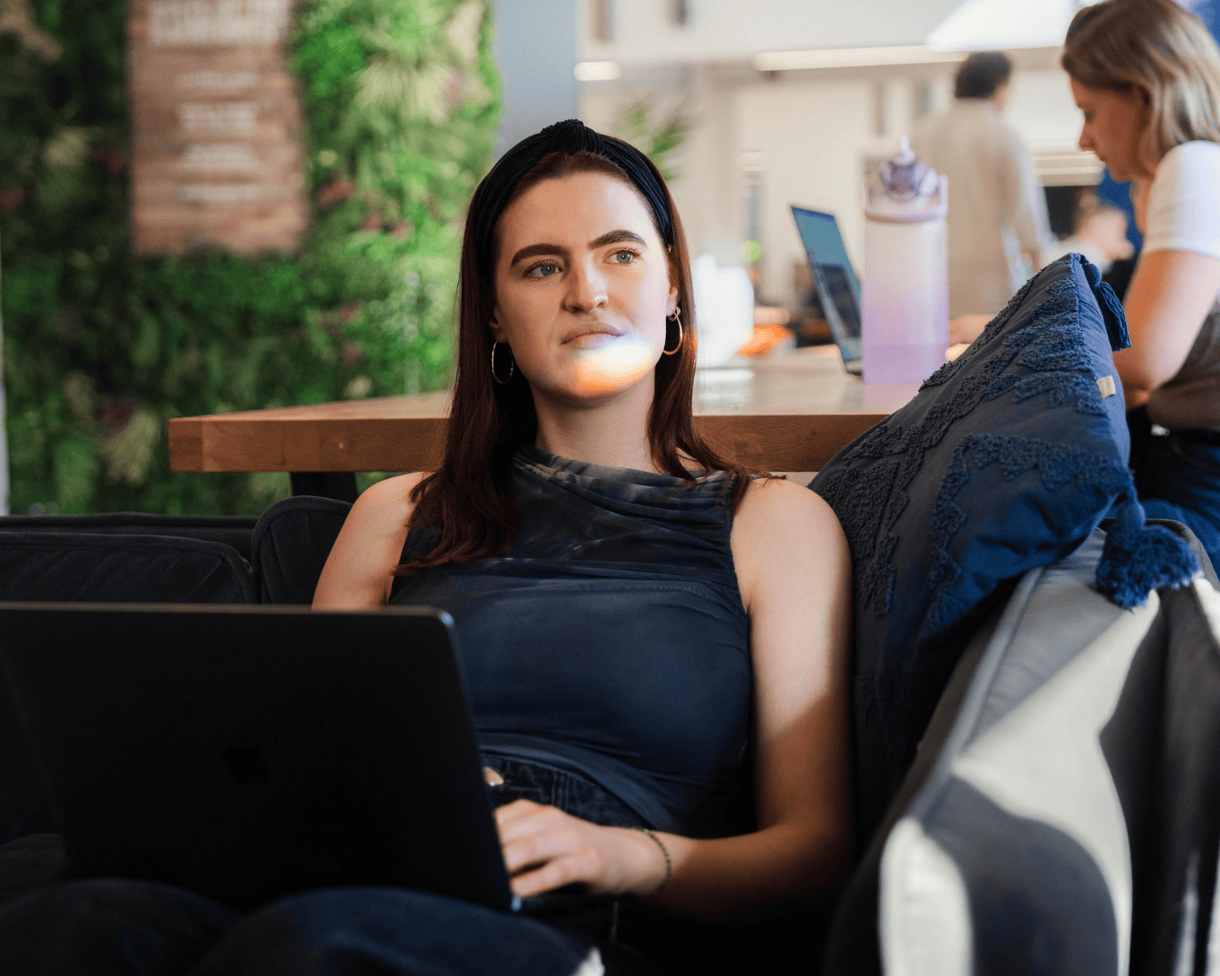 photo of female woth red hair sat on the sofa with a laptop on her lap