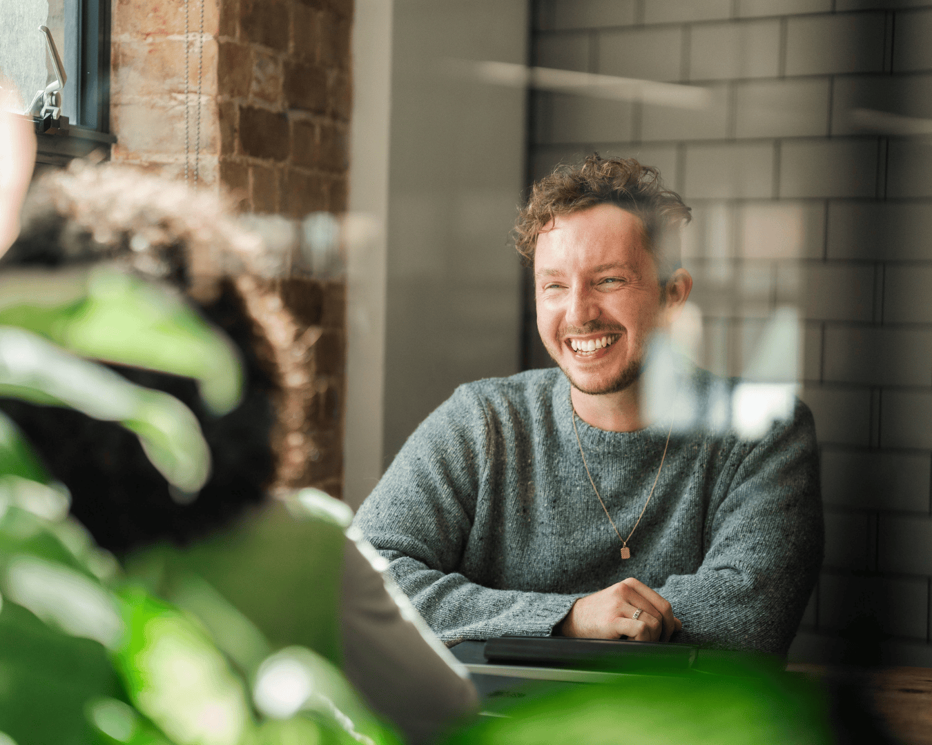 Photo of man with blonde hair smiling through glass looking someone in front of him