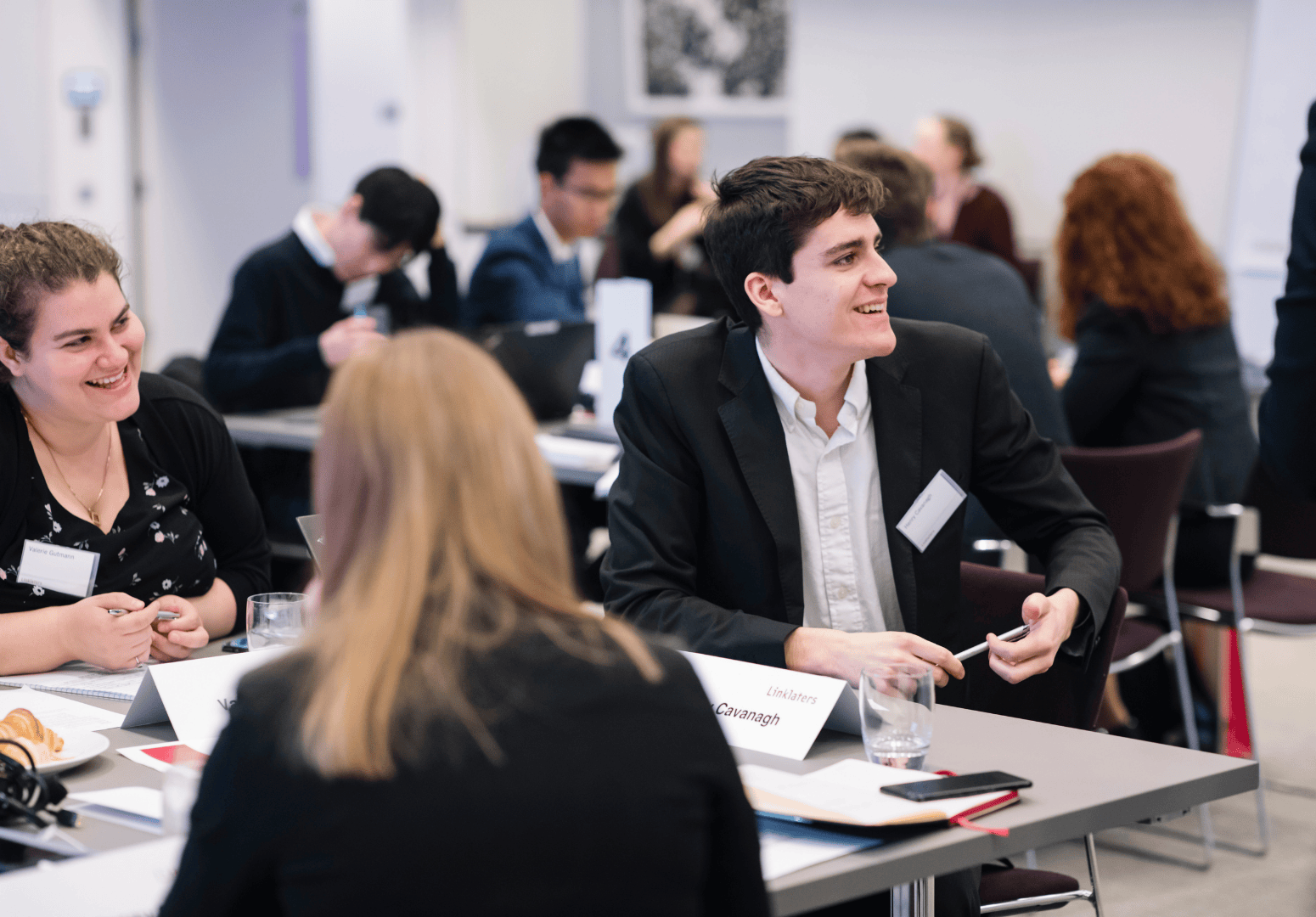 Photo of man with dark hair in a suit sat at a desk