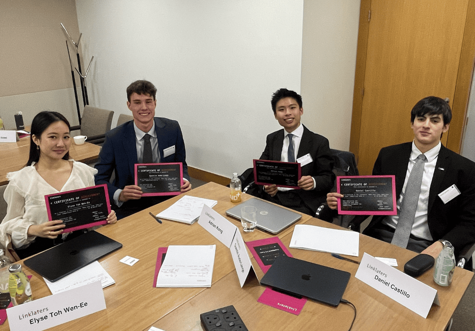 Photo of students sat around a desk with certificates