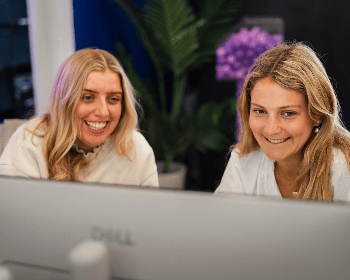 Two females looking at a laptop screen smiling in an office
