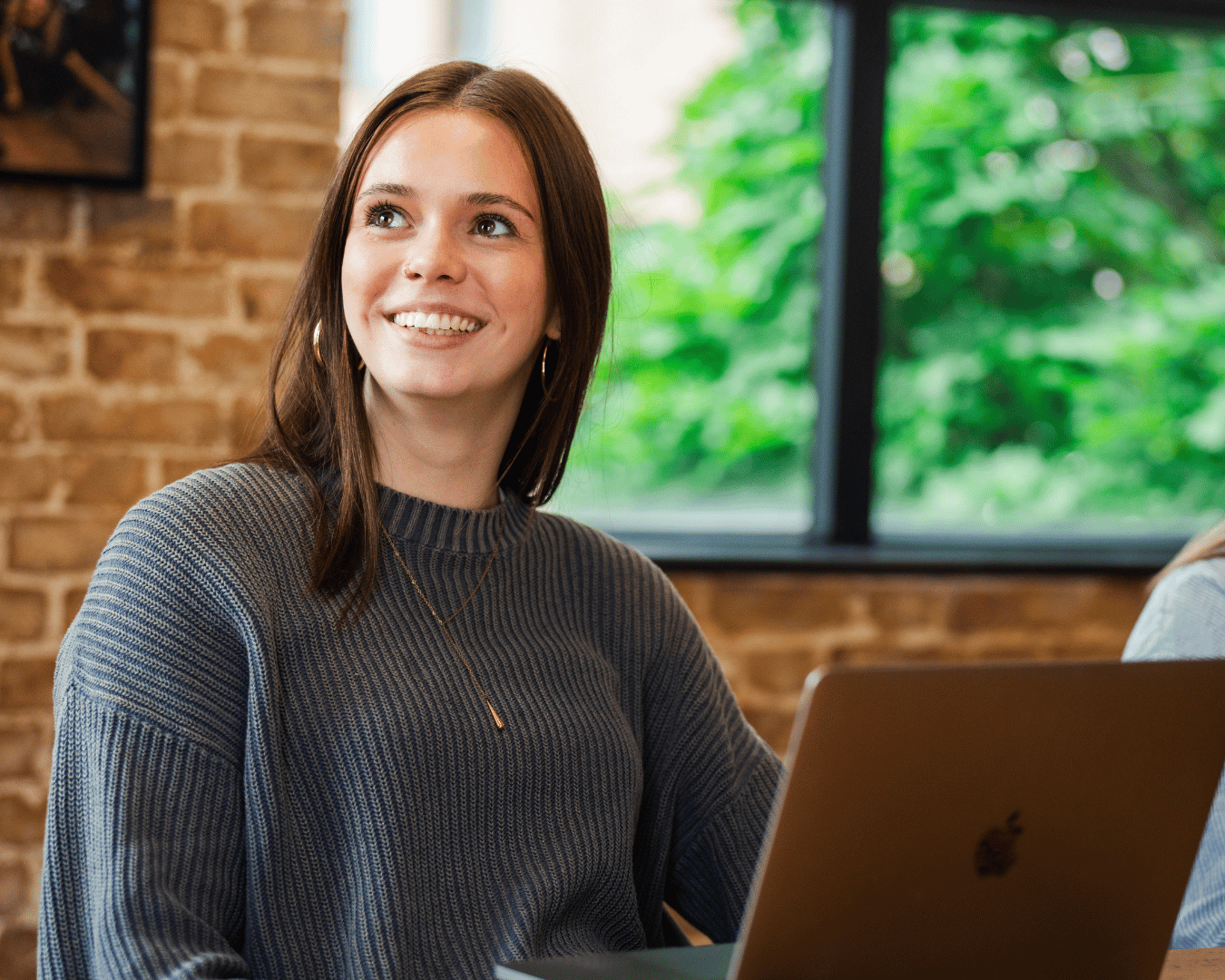 photo of a female in office with a grey jumper smiling looking at a screen