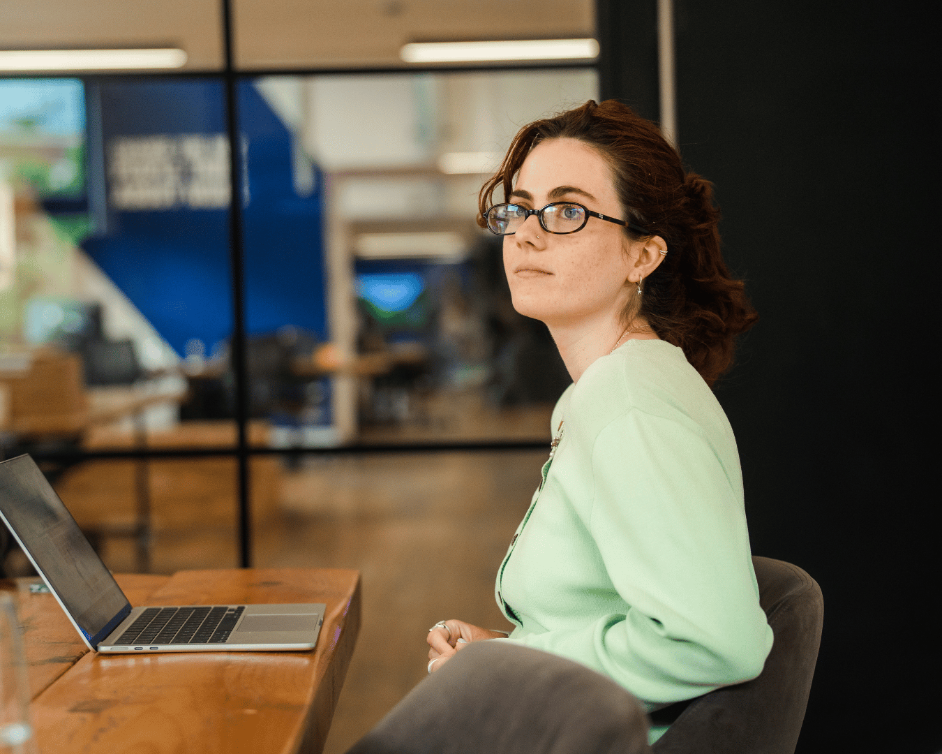 Two colleagues standing at a table and working together on laptops in a modern office environment.