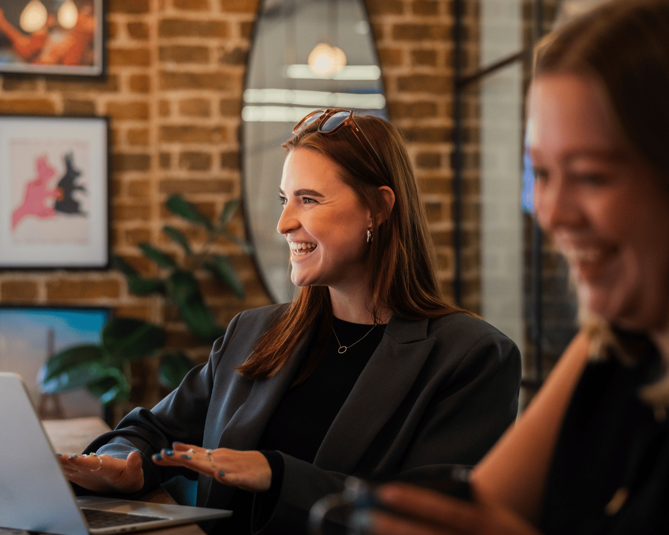 photo of a female with red hair, wearing a black blazer smiling in a meeting room