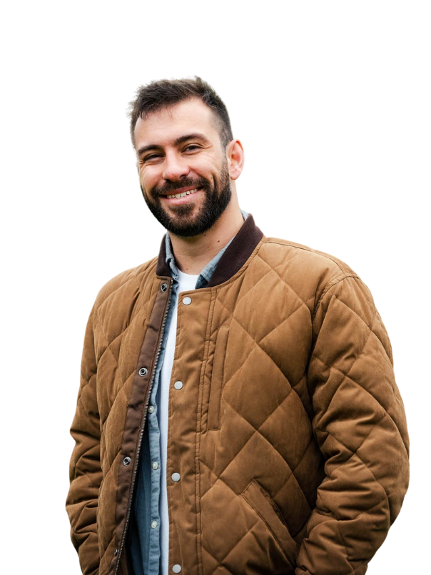 Photo of a man smiling with brown hair, wearing a quilted jacket