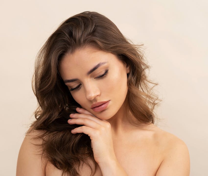 woman posing with hand on her cheek/chin as she looks down