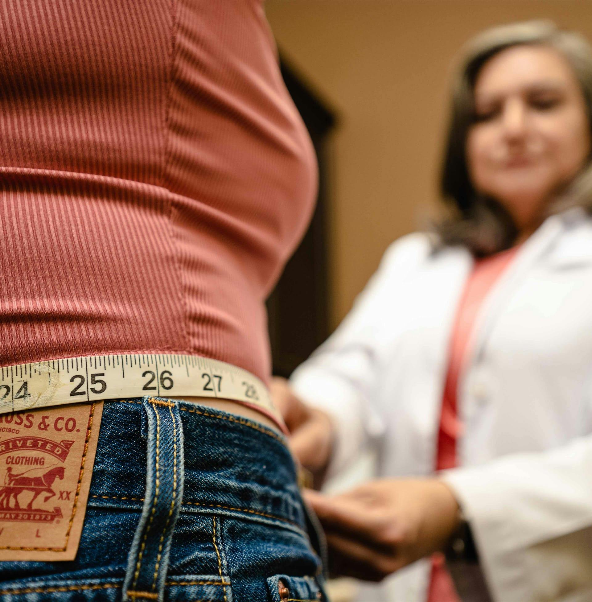close up of doctor measuring client's waist