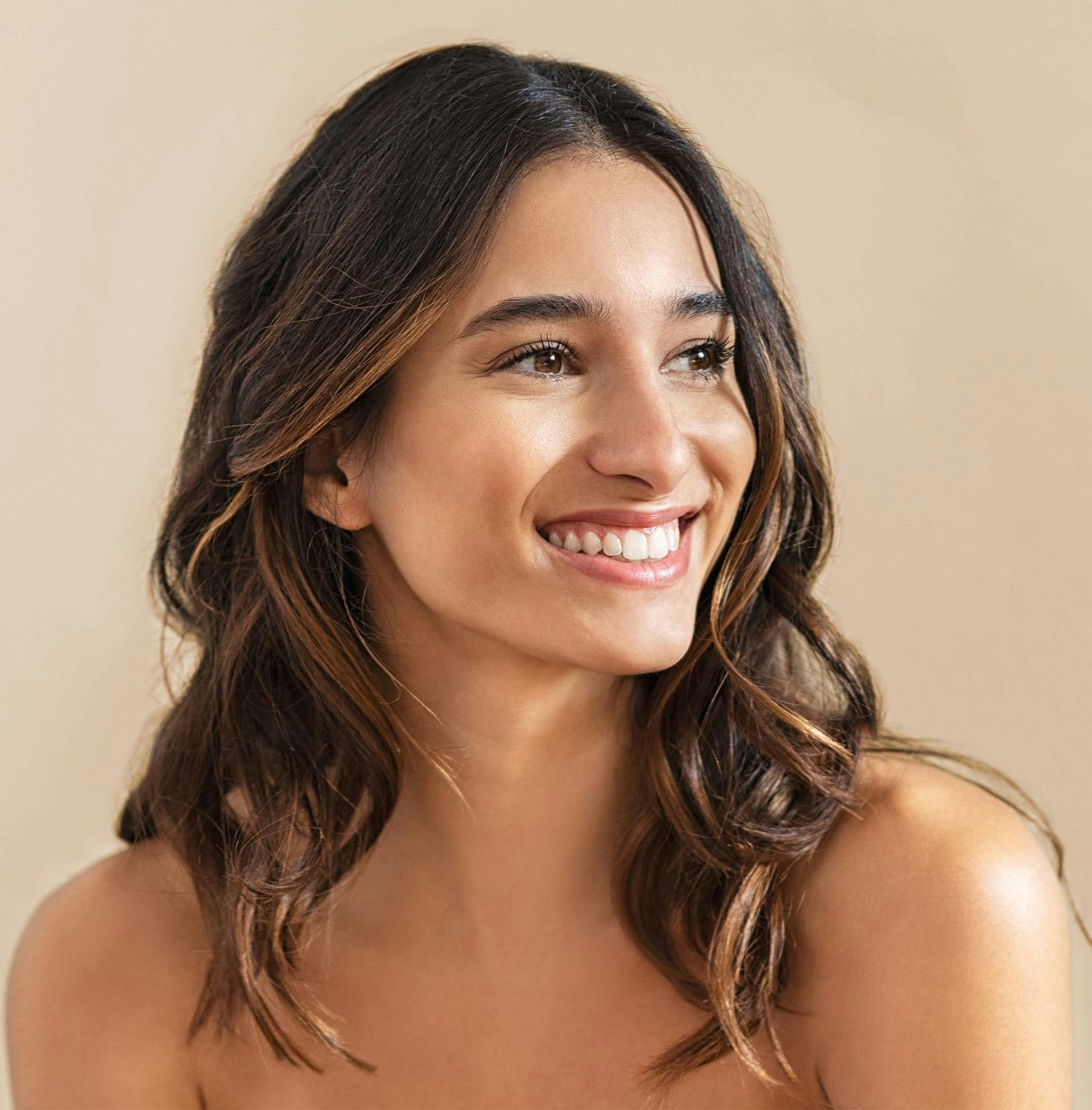 woman smiling off to the side with wavy brown hair