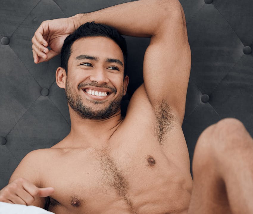 man posing against headboard of bed