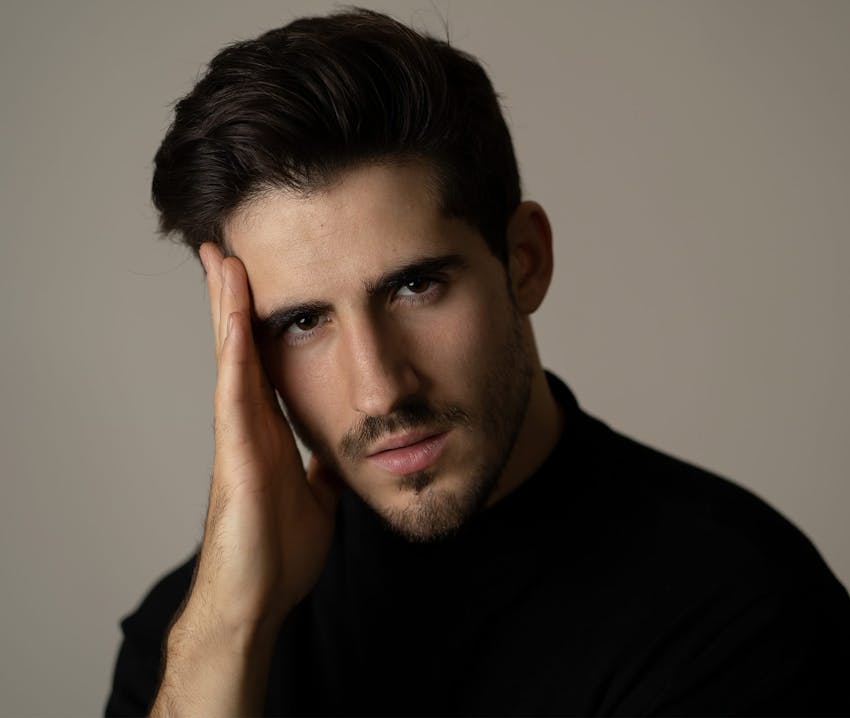 man in black turtleneck with hand near forehead